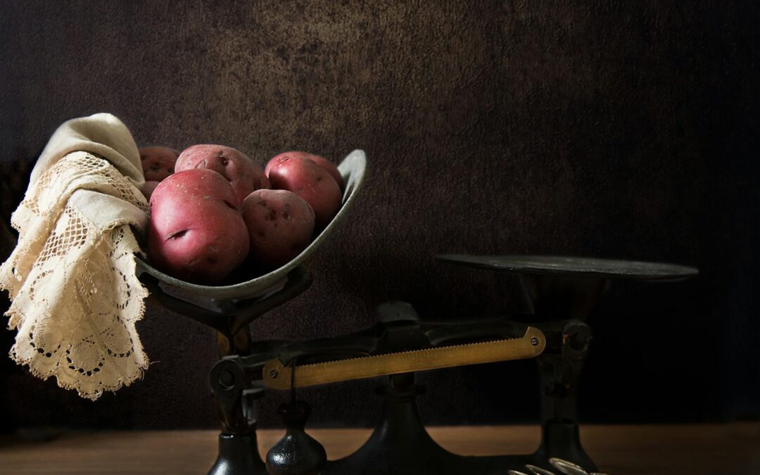 Vintage balance scale with red potatoes and lace cloth, evoking a nostalgic rustic feel.