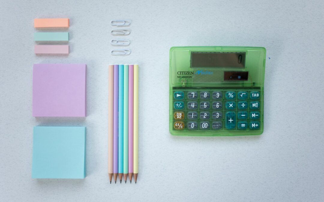 Flat lay of pastel stationery including a colorful calculator and pencils.